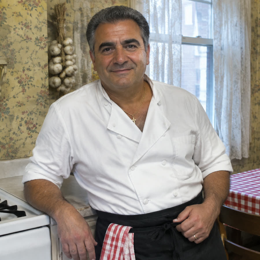 Angelo Ferrara in his white cook's jacket, leaning on the counter of his Brooklyn kitchen